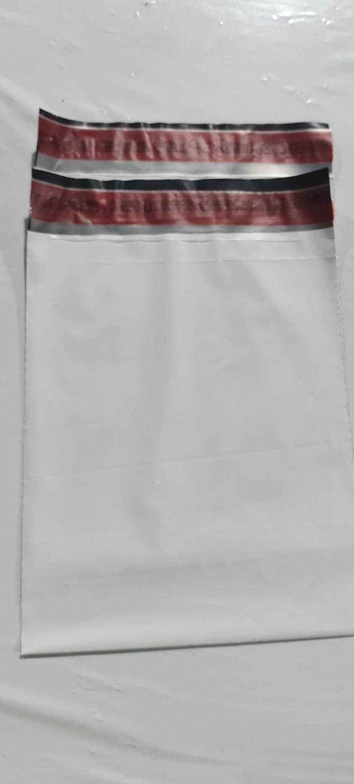 White poly mailer sealed with a red tamper-evident security closure across the flap